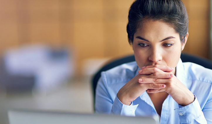 Woman with a tense expression looks at computer screen. Market and consumer insights researchers need to prioritize security.