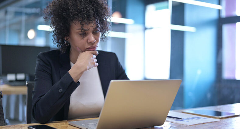 Pre-curated content can have real ROI for knowledge management users like the young Black professional woman working at her laptop pictured here.