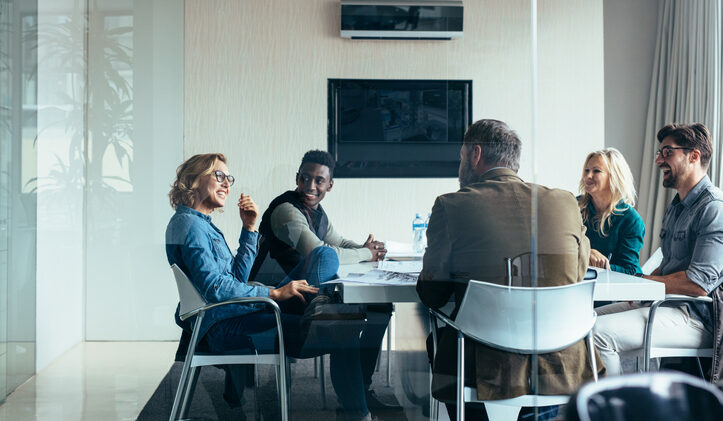 A diverse consumer insights research team meets around a conference table.