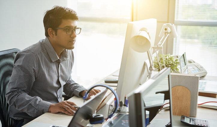 A programmer sits at his desk working on a knowledge management system