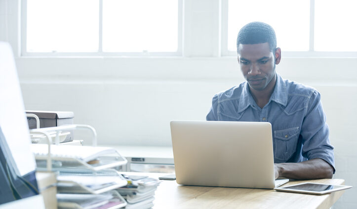 A man works intently at a laptop. Knowledge management systems help you know what you don't know.