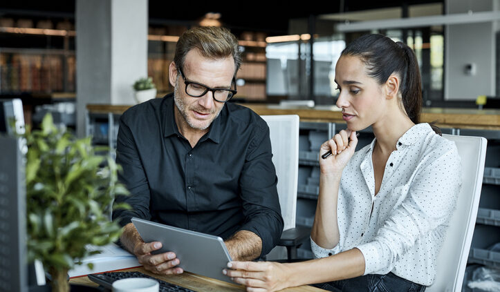 A man and woman look at a tablet together in a modern office. What is the role of AI in knowledge management?