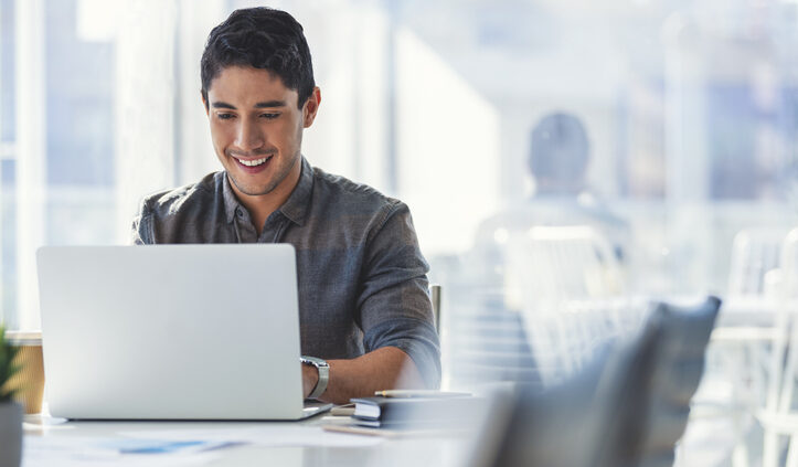 Young man happily works at laptop. SinglePoint eliminates content silos.