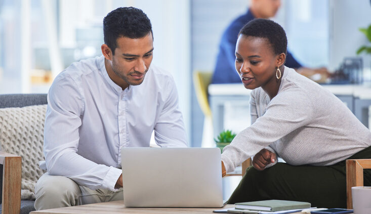 Shot of two businesspeople discussing something on a laptop while sitting together in an office. Digital transformation and the IT sector.