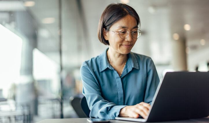 Competitive intelligence professional works at her laptop in a sunlit office.