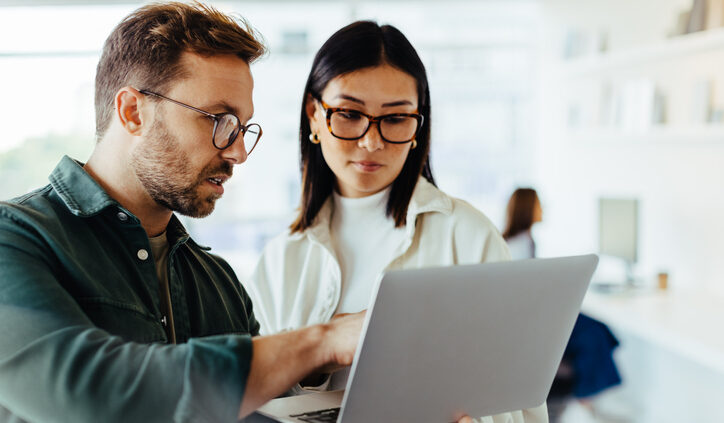 Design professionals using a laptop together in an office. Generative AI in businesss.