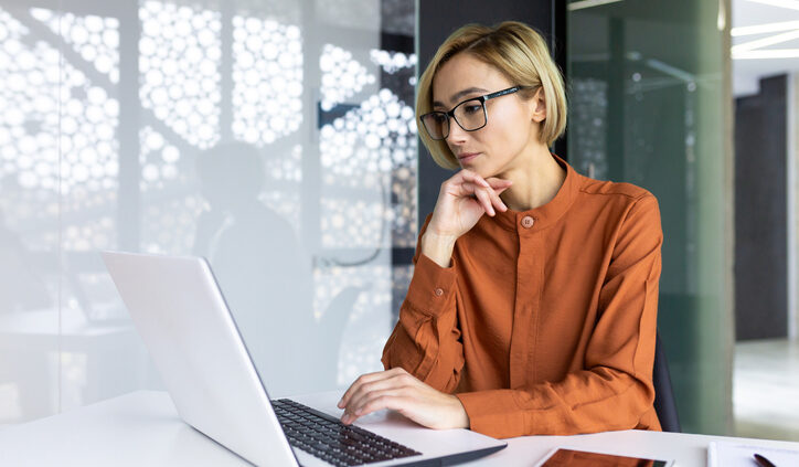 Serious thinking woman working with laptop inside office at workplace, businesswoman solving technical task, female programmer coding new software. Generative AI.